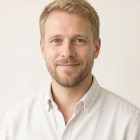 Nils Halvorsen in a white oxford shirt against a cream backdrop